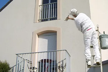 homme entrain de peindre une façade de maison